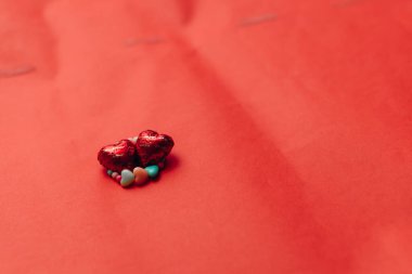 Sevgililer Günü. Kırmızı masada bilezik ve iki kalp şeklinde şeker var.