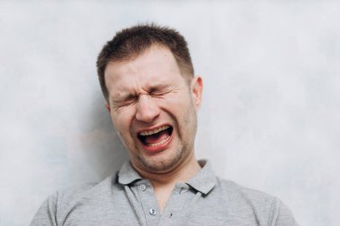 Gri tişörtlü yakışıklı blogcu elinde telefon tutuyor ve abonelerle iletişim kuruyor.