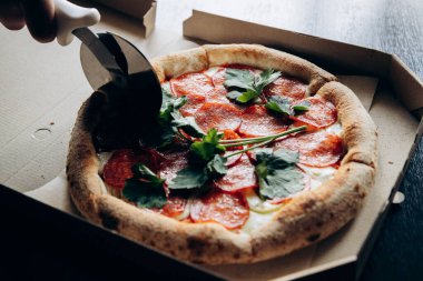 Lezzetli ve sulu İtalyan pizzası sosisli ve bıçakla kesilmiş.