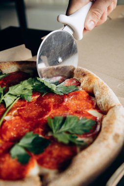 Lezzetli ve sulu İtalyan pizzası sosisli ve bıçakla kesilmiş.