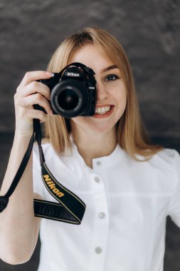 Beyaz önlüklü genç erkek dişçiler bir kamera tutuyor ve gülümsüyor.