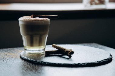 Masanın üzerinde tarçınlı beyaz bir fincan lezzetli kahve duruyor.