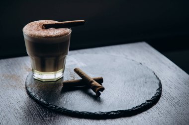 Masanın üzerinde tarçınlı beyaz bir fincan lezzetli kahve duruyor.