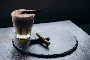 Masanın üzerinde tarçınlı beyaz bir fincan lezzetli kahve duruyor.