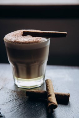 Masanın üzerinde tarçınlı beyaz bir fincan lezzetli kahve duruyor.