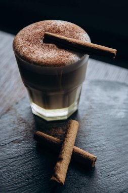 Masanın üzerinde tarçınlı beyaz bir fincan lezzetli kahve duruyor.