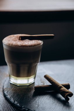 Masanın üzerinde tarçınlı beyaz bir fincan lezzetli kahve duruyor.