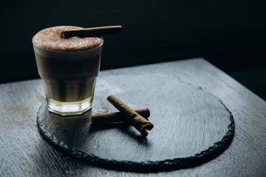 Masanın üzerinde tarçınlı beyaz bir fincan lezzetli kahve duruyor.