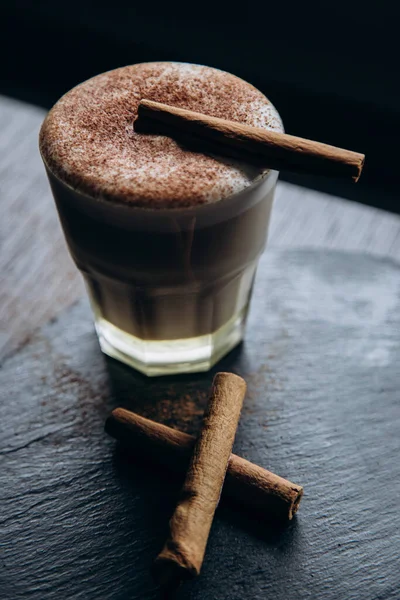 Masanın üzerinde tarçınlı beyaz bir fincan lezzetli kahve duruyor.