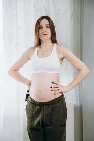 Gravid Långhårig Flicka Gröna Byxor Står Nära Fönstret — Stockfoto