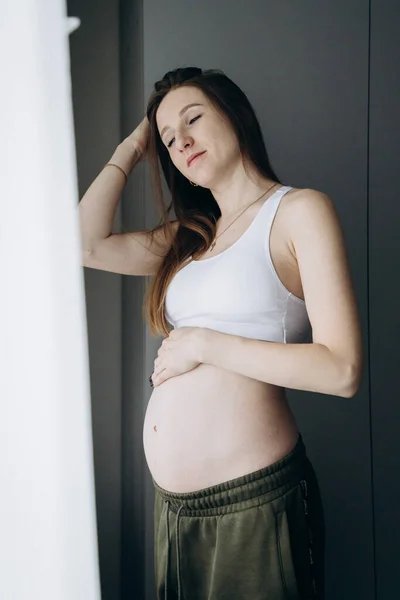 Embarazada Chica Pelo Largo Pantalones Verdes Para Cerca Ventana —  Fotos de Stock