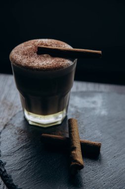 Masanın üzerinde tarçınlı beyaz bir fincan lezzetli kahve duruyor.