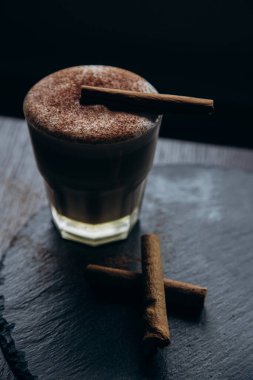 Masanın üzerinde tarçınlı beyaz bir fincan lezzetli kahve duruyor.