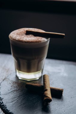 Masanın üzerinde tarçınlı beyaz bir fincan lezzetli kahve duruyor.