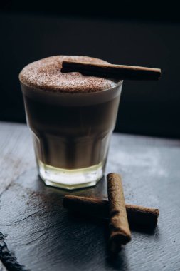 Masanın üzerinde tarçınlı beyaz bir fincan lezzetli kahve duruyor.