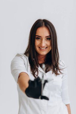 Beyaz önlüklü bir dişçi elinde bir şırınga tutuyor.