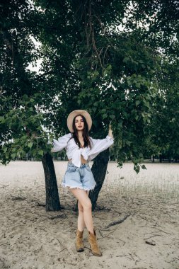 Beyaz gömlekli ve mayosuyla bronzlaşmış seksi vücudu olan mutlu bir genç kızın güzel sarışın bir kadının portresi tropikal bir adada berrak bir suyla duruyor.