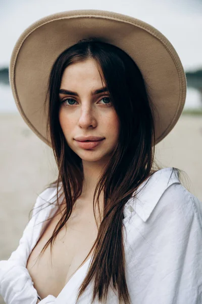 热带岛屿上的海滩上 站着一位美丽的金发女子 头戴一顶幸福的帽子 身穿白衬衫 身穿泳衣 皮肤晒黑的性感少女的夏季生活方式画像 — 图库照片