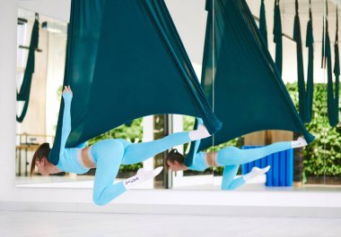 Atletik güzel kız sinek yogası yapıyor ve karantinada geriniyor