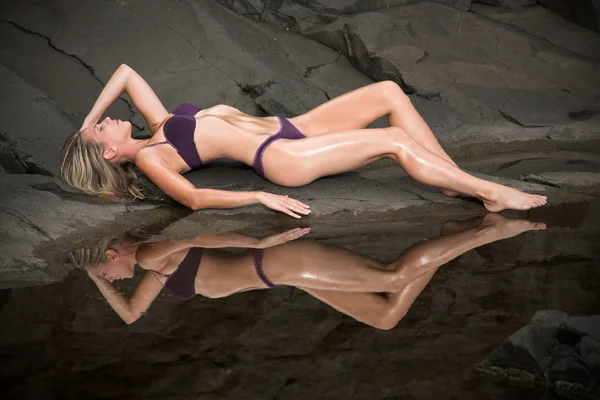Piękny i sexy kobieta leży na skały w pobliżu wody. — Zdjęcie stockowe