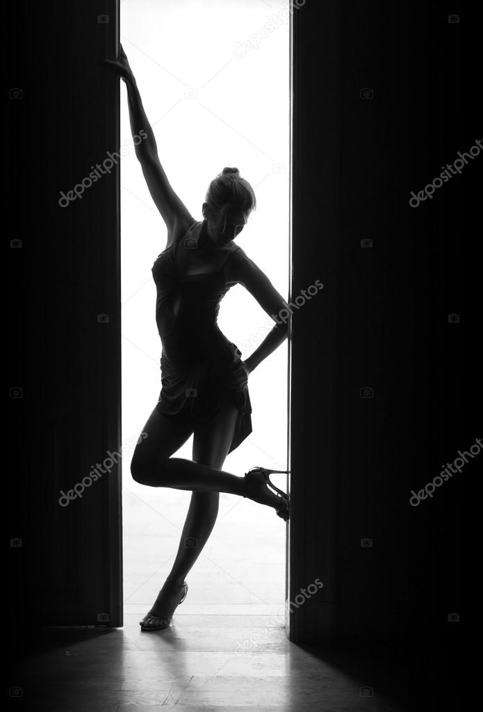 Bueutiful, sexy dancer woman stands in doorway, silhouette