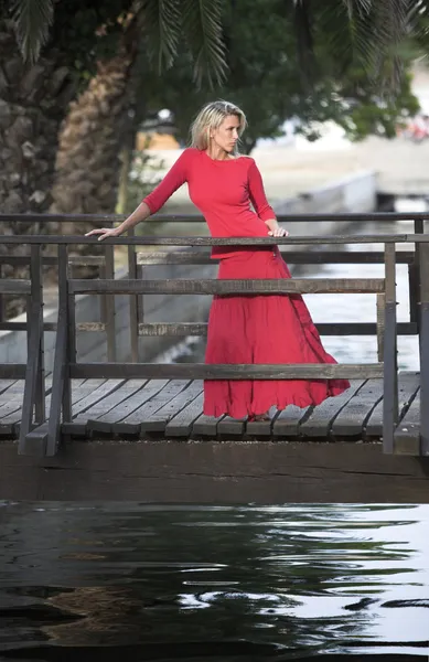 Beutiful woman in red dress, wooden bridge — Stock Photo, Image