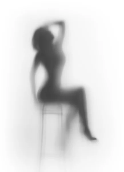 Piękna kobieta siedzi na krześle, za powierzchnię szkła rozproszonych — Zdjęcie stockowe