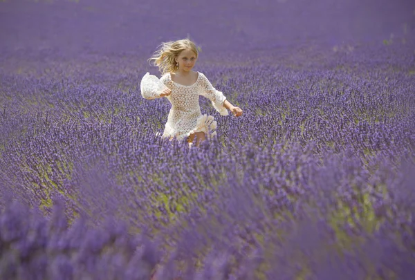 Happy little girl jumps in field of lavender — Stock Photo, Image