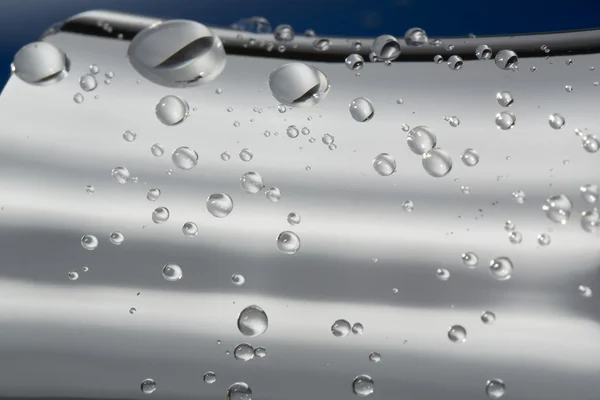 Gotas de agua en una plata y azul —  Fotos de Stock