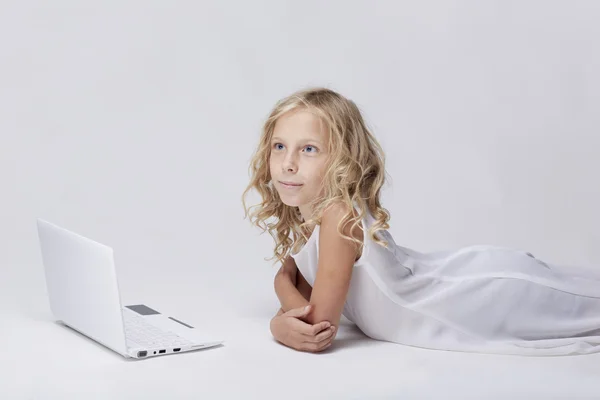 Vacker blond liten flicka med netbook, vit bakgrund — Stockfoto