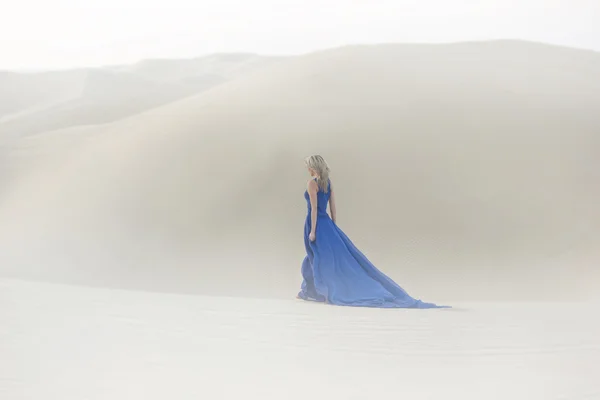 Beautiful young woman walks in desert, long, blue dress — Stock Photo, Image