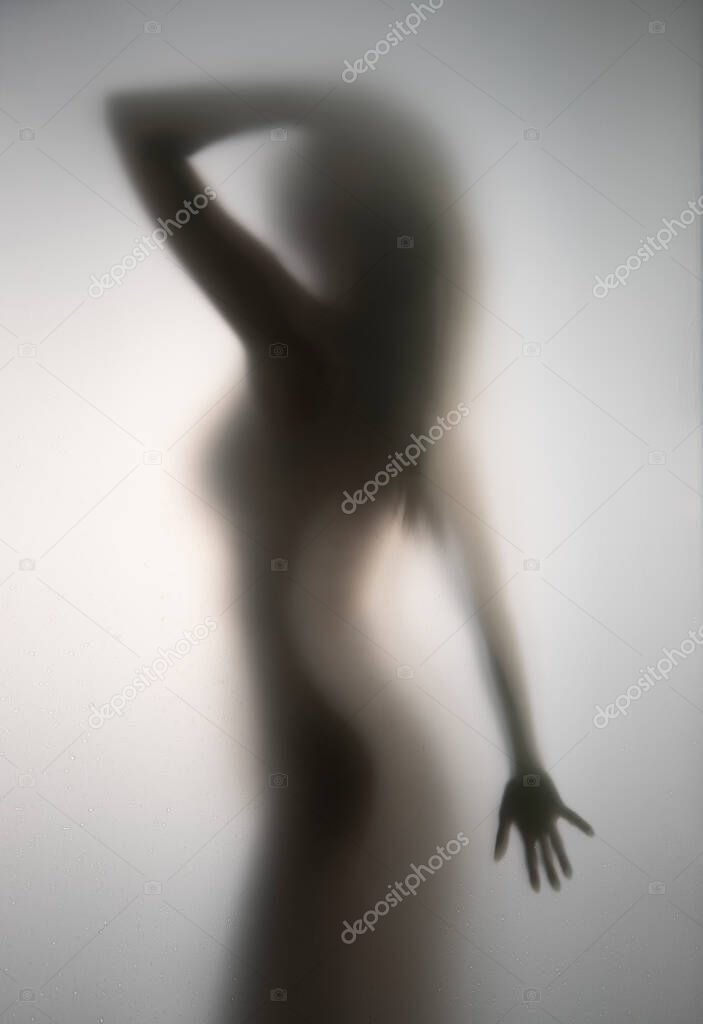 Beautiful woman body shape can be seen through a translucent glass wall.