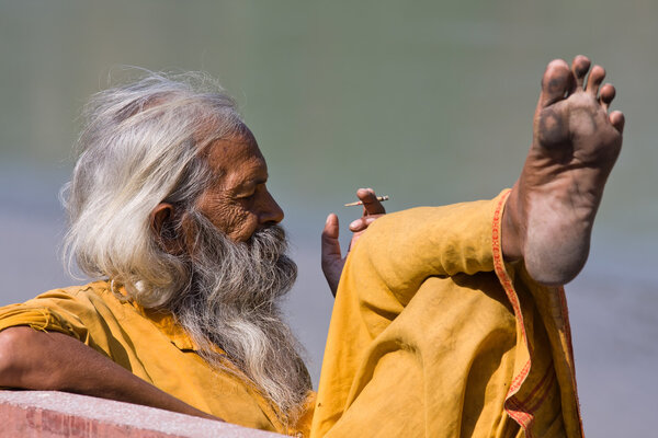 RISHIKESH, INDIA - OCTOBER 24: An unidentified portrait sadhu sits on the ghat along the Ganges on October 24, 2012 in Rishikesh, India. Tourism has drawn many alleged fake sadhus to Rishikesh