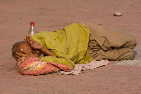 HARIDWAR, INDIA - NOV 8: An unidentified homeless man sleeps on the sidewalk near the River Ganges on November 8, 2012 in Haridwar, India. Poor Indians flock to Haridwar for charity. — Stock Photo, Image