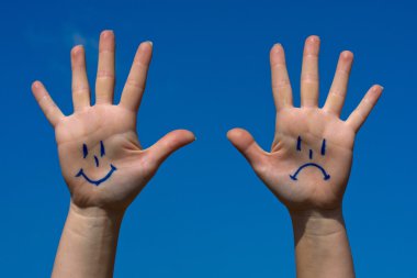 Hands with smiles and sadness pattern against the blue sky clipart