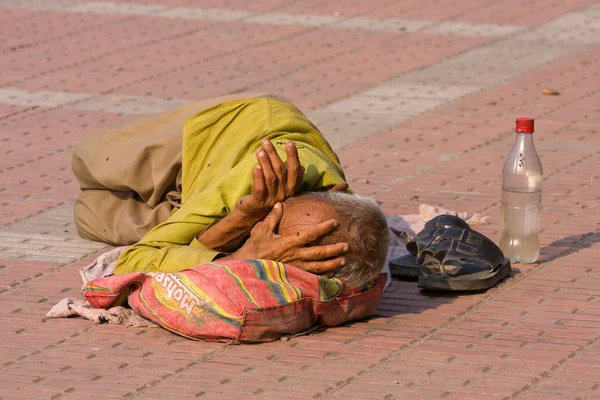 HARIDWAR, INDIA - NOV 8: An unidentified homeless man sleeps on the sidewalk near the River Ganges on November 8, 2012 in Haridwar, India. Poor Indians flock to Haridwar for charity. — Stock Photo, Image