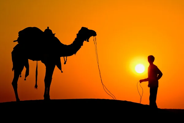 Silhouet van een man en de kameel bij zonsondergang in de woestijn, jaisalmer - india — Stockfoto