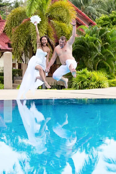 Bride and groom jumping in swimming pool — Stock Photo, Image
