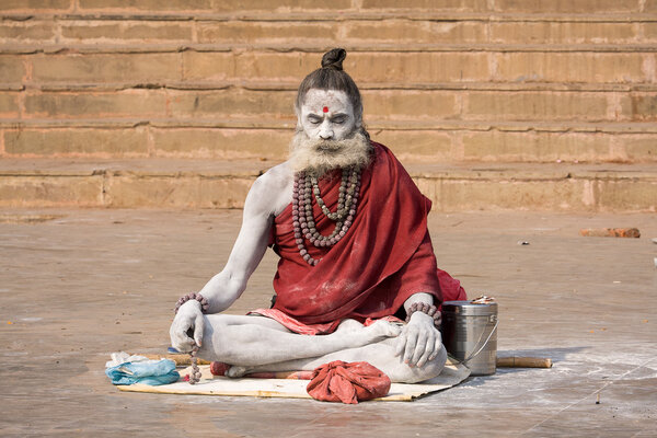 Садху сидит на гате вдоль реки Ганг в Варанаси, Индия
.