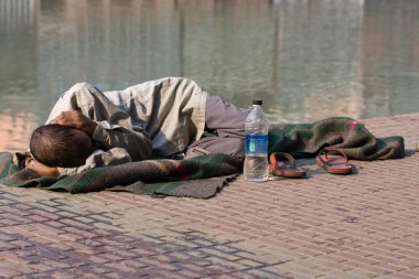 evsiz adam nehir Ganj haridwar, Hindistan'ın yakınlarında kaldırımda yatıyor.