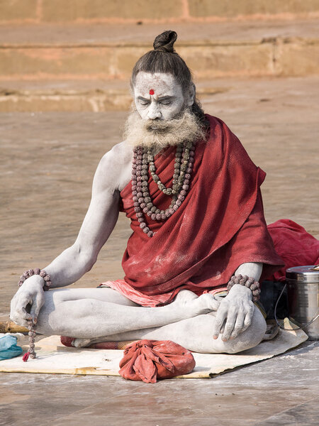 Sadhu sits on the ghat along the Ganges river in Varanasi, India.