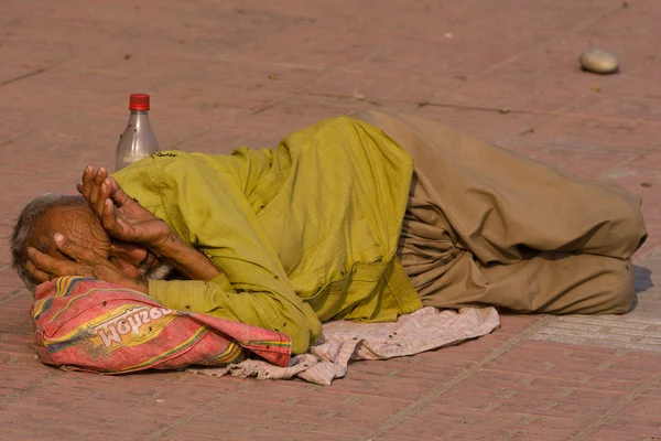 Dakloze man slaapt op de stoep in de buurt van de rivier de ganges in haridwar, india. — Stockfoto