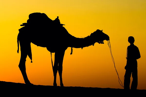 Silhouet van een man en de kameel bij zonsondergang in de woestijn, jaisalmer - india — Stockfoto