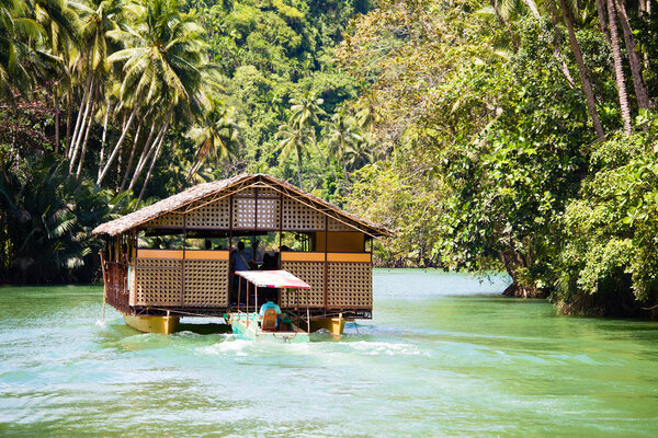 Exotic cruise boat with tourists on a jungle river. Island Bohol, Philippines.