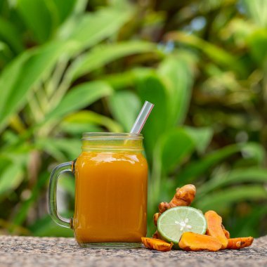 Zerdeçal, zencefil, limon ve ballı enerji içeceği cam bardak, doğa arka planı, kapat