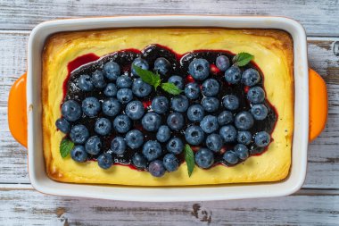 Beyaz ahşap arka planda yaban mersinli cheesecake, üst manzara, kapat