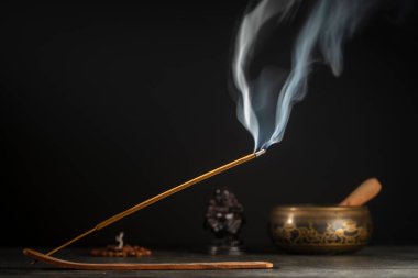 Çubuk tutacağındaki Asya tütsü çubuğu siyah arka planda dumanla yanıyor, yakın çekim, kopyalama alanı. Meditasyon, yoga, kişisel gelişim ve ses terapisi kavramı