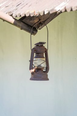 Macaristan 'ın Holloko kentindeki etnografik bir köyün arka bahçesinde beyaz bir duvar arkasına asılı eski paslı bir gaz lambası.
