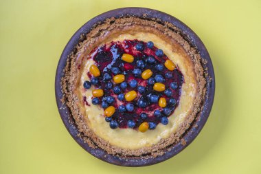 Sarı arka planda yabanmersini ve deniz dikenli cheesecake, üst manzara, kapat