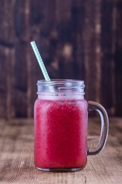 Ahşap arka plandaki cam kavanozda taze çilekli smoothie, yakın çekim. Sağlıklı gıda konsepti